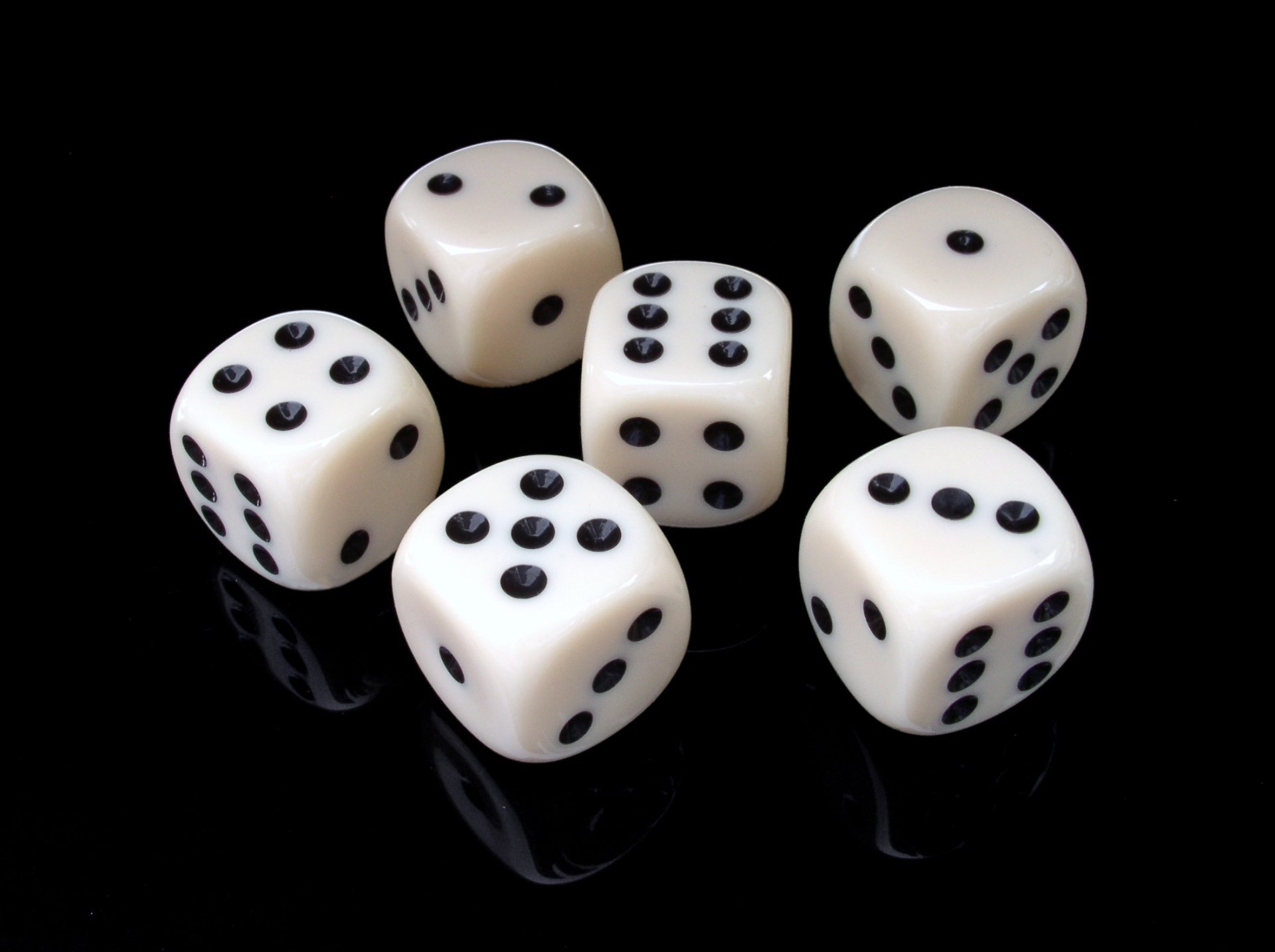 An HD desktop wallpaper featuring six white dice with black dots, set against a sleek black background, showcasing their man-made design and numeric details.