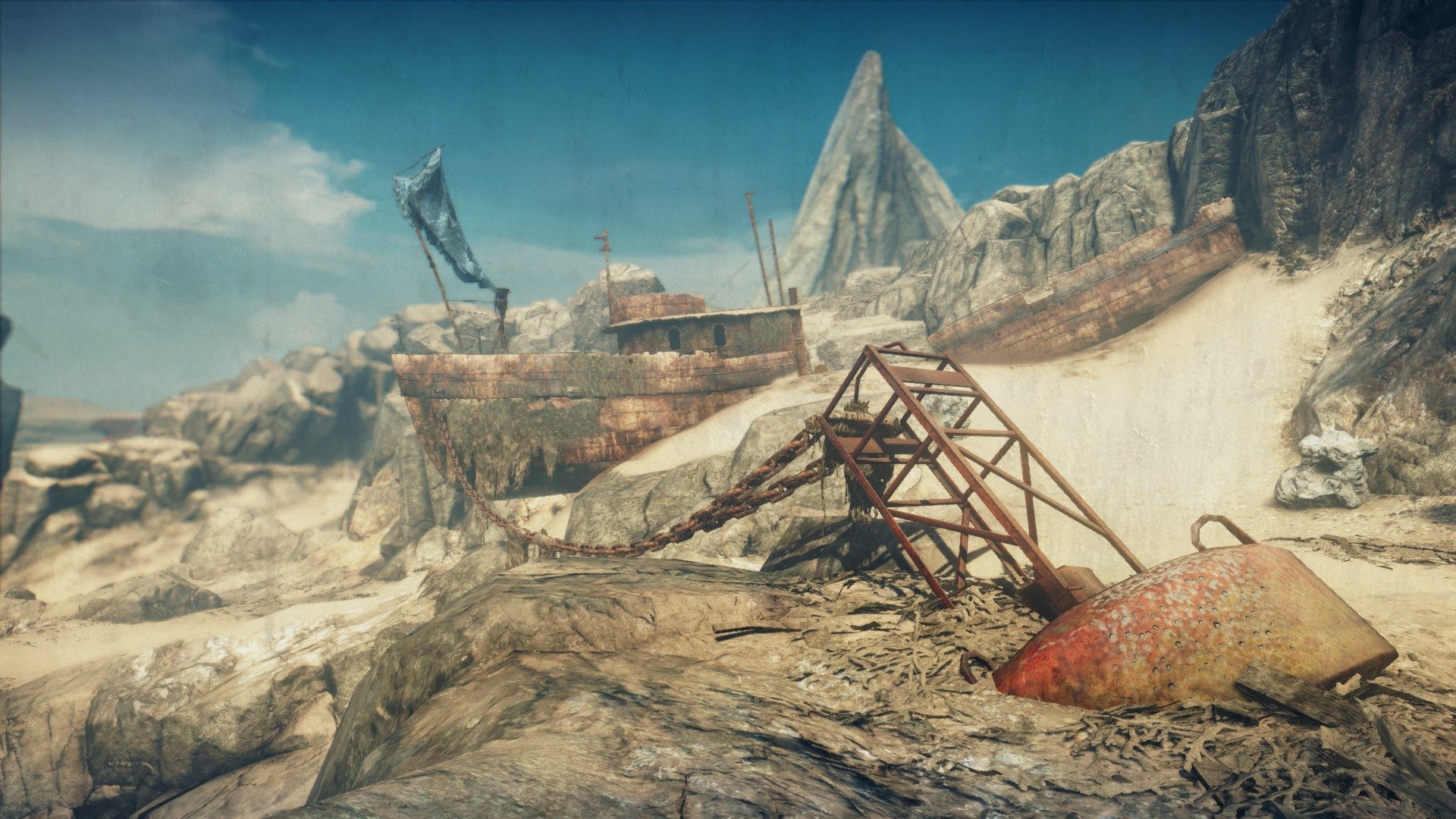 HD PC desktop wallpaper from the Mad Max video game: desolate rocky wasteland scattered with rusted vehicle wreckage and a collapsed metal frame beneath a blue sky.