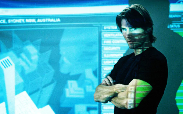 Arms-crossed man with a bandana-like face covering standing before blue tactical displays — Mission: Impossible II movie HD PC desktop wallpaper/background.