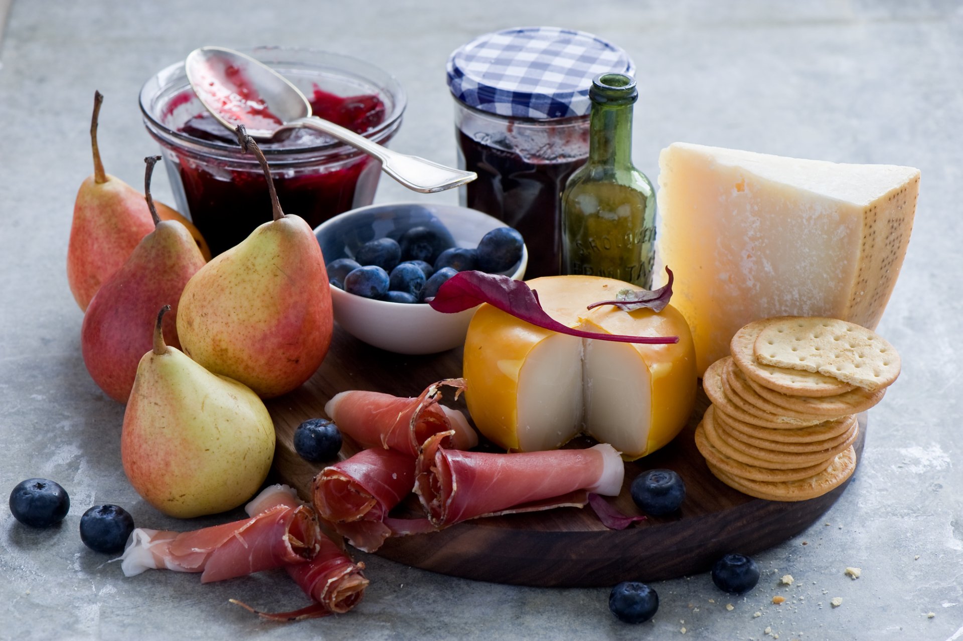 HD desktop wallpaper of a still life featuring pears, blueberry jam, cheese, crackers, and cured meat arranged on a rustic surface.