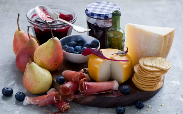HD desktop wallpaper of a still life featuring pears, blueberry jam, cheese, crackers, and cured meat arranged on a rustic surface.