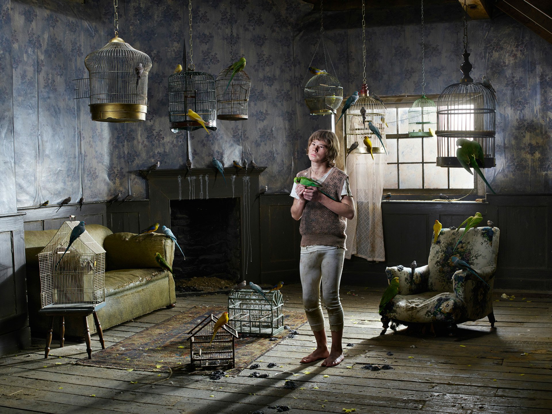 A fantasy-themed HD PC desktop wallpaper depicting a young girl in a dim, abandoned room filled with empty birdcages and vintage furniture, evoking a fairy tale atmosphere.