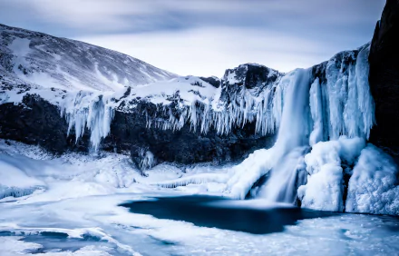 HD PC desktop wallpaper: a frozen winter waterfall with hanging icicles and sculpted ice over a snow-covered landscape.
