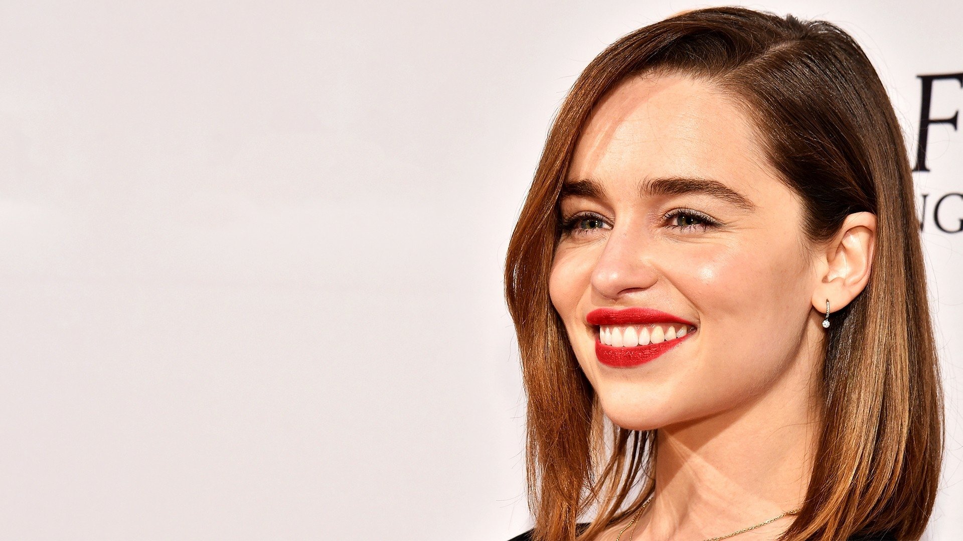 HD PC desktop wallpaper featuring a close-up portrait of celebrity Emilia Clarke smiling against a light background.