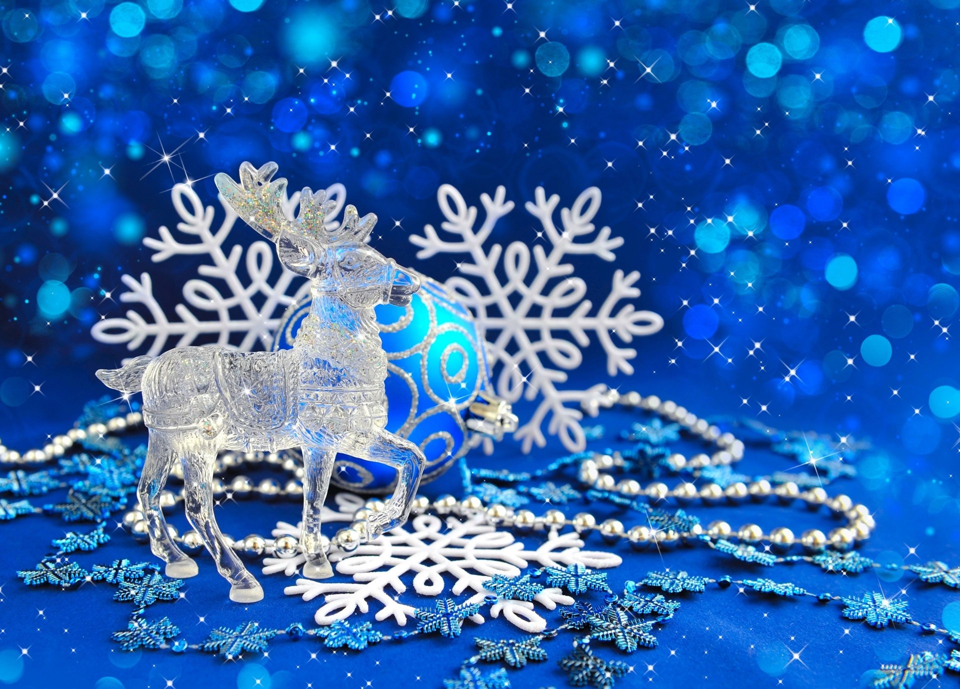 A 4K Ultra HD holiday desktop wallpaper featuring blue Christmas ornaments, white snowflakes, and a sparkling silver deer against a vibrant blue bokeh background.
