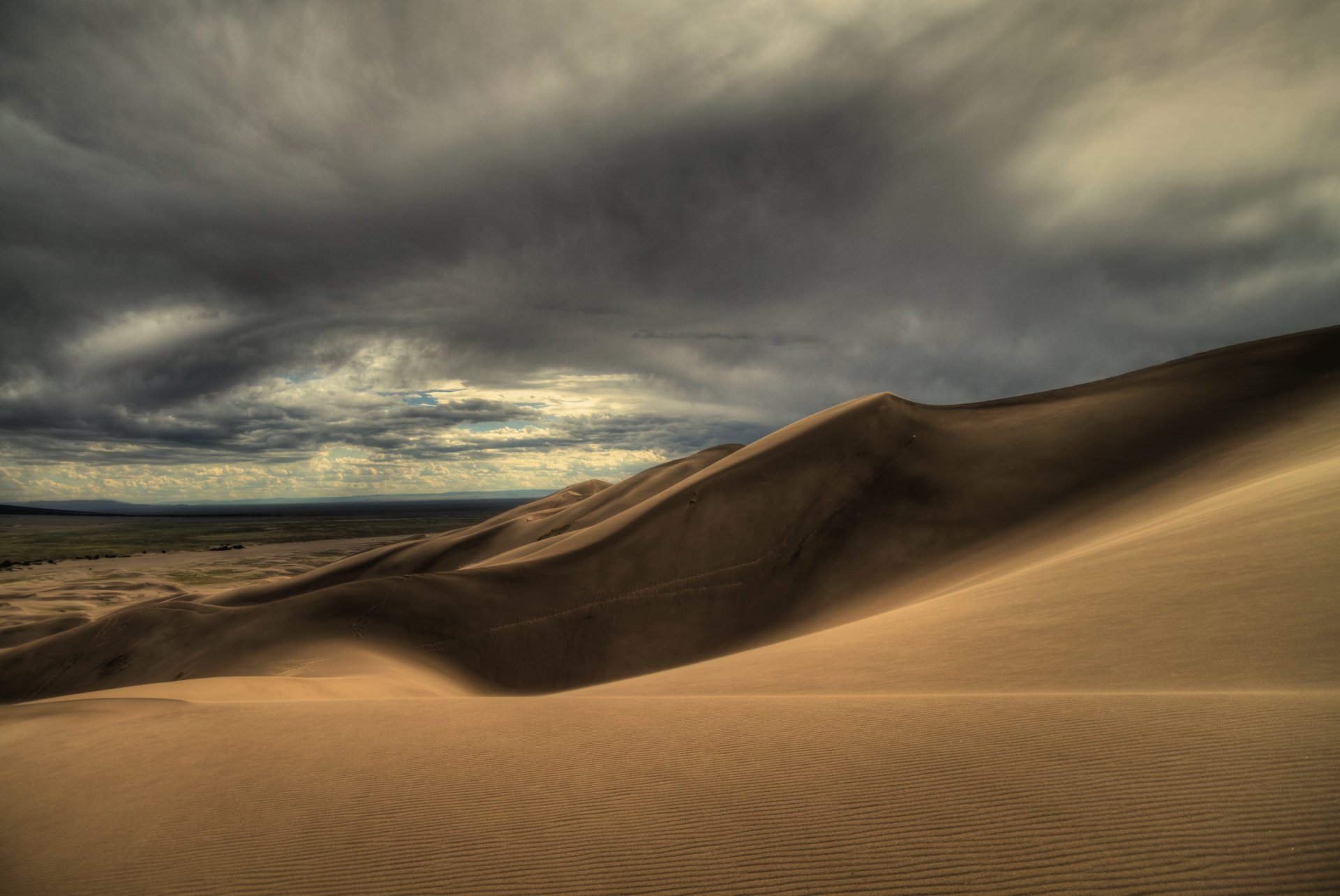 A 4K Ultra HD desert landscape wallpaper showcasing rolling sand dunes under a dramatic cloudy sky, capturing the raw beauty of nature in high detail.