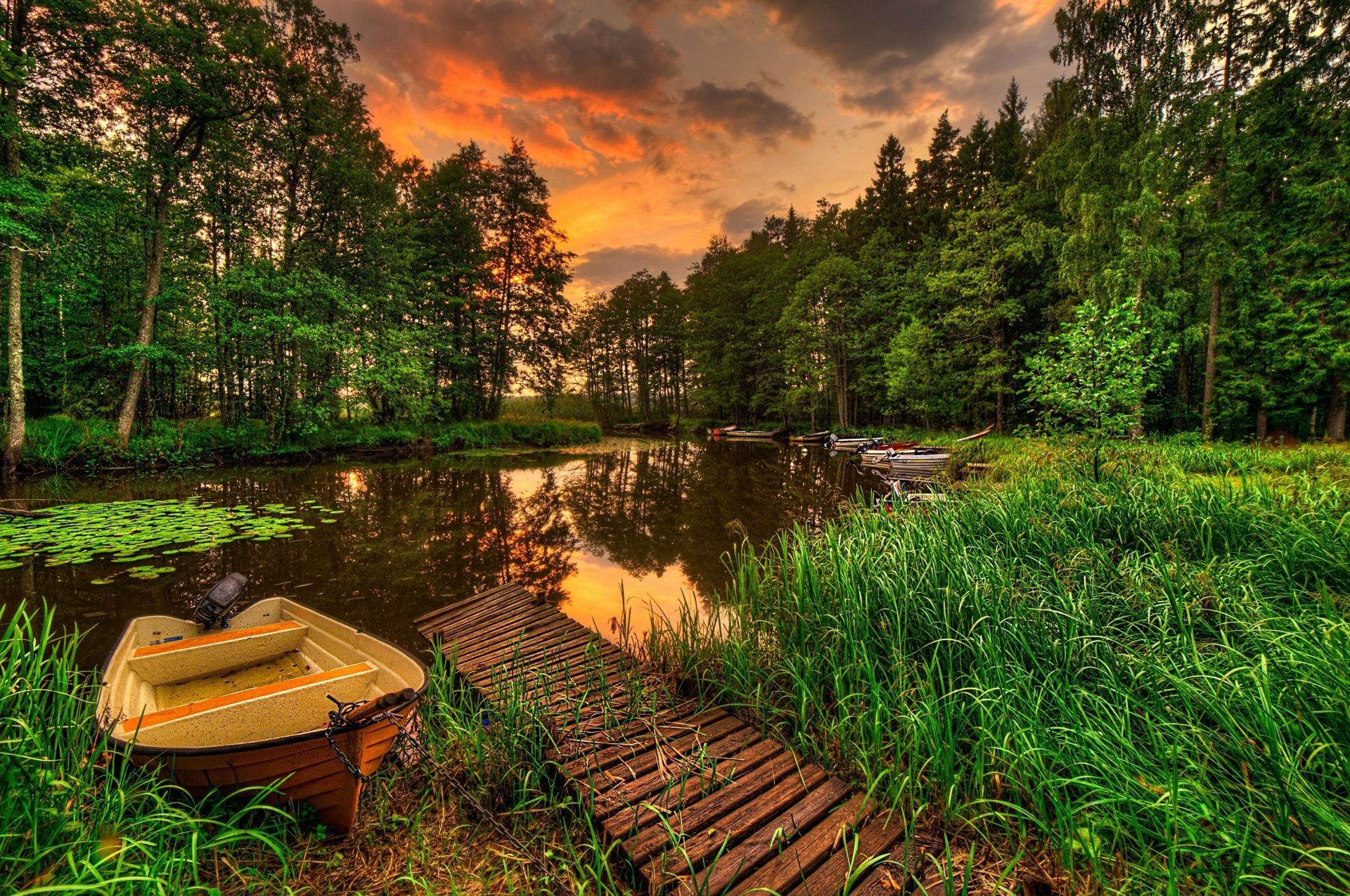 4K Ultra HD photography of a serene lake at sunset with a small boat, wooden dock, lush greenery, and vibrant sky, creating a tranquil desktop wallpaper and background.