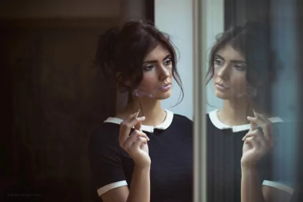 A brunette model with brown eyes gazes thoughtfully at her reflection, exhaling cigarette smoke, creating a moody atmosphere in this HD desktop wallpaper.