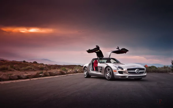 A silver Mercedes-Benz SLS AMG supercar with gullwing doors open, parked on a road at sunset, featured as an HD PC desktop wallpaper and background.