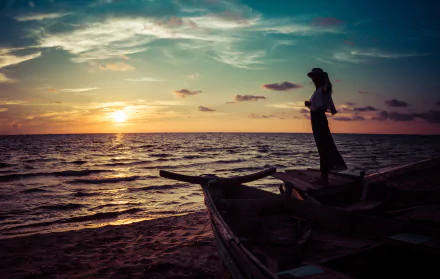 A woman wearing a hat stands on a boat by the sea, gazing at a vibrant summer sunset, captured in stunning 4K Ultra HD for a serene mood.