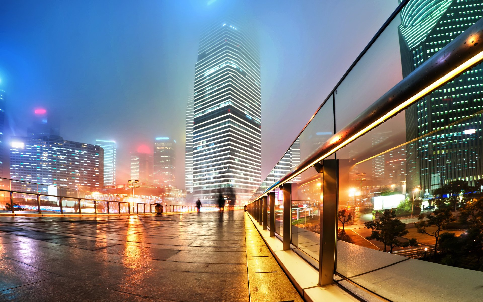 A vibrant 4K Ultra HD nighttime view of Shanghai’s illuminated metropolis in China, showcasing towering skyscrapers and glowing city lights through a misty atmosphere.