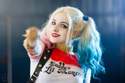 A woman cosplaying as Harley Quinn, featuring vibrant hair and a playful pose, creates a dynamic HD desktop wallpaper and background.