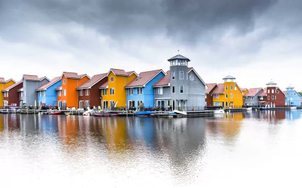 Colorful man-made houses line a calm lake in Groningen, Netherlands, reflecting vibrant hues in this HD desktop wallpaper and townscape background.