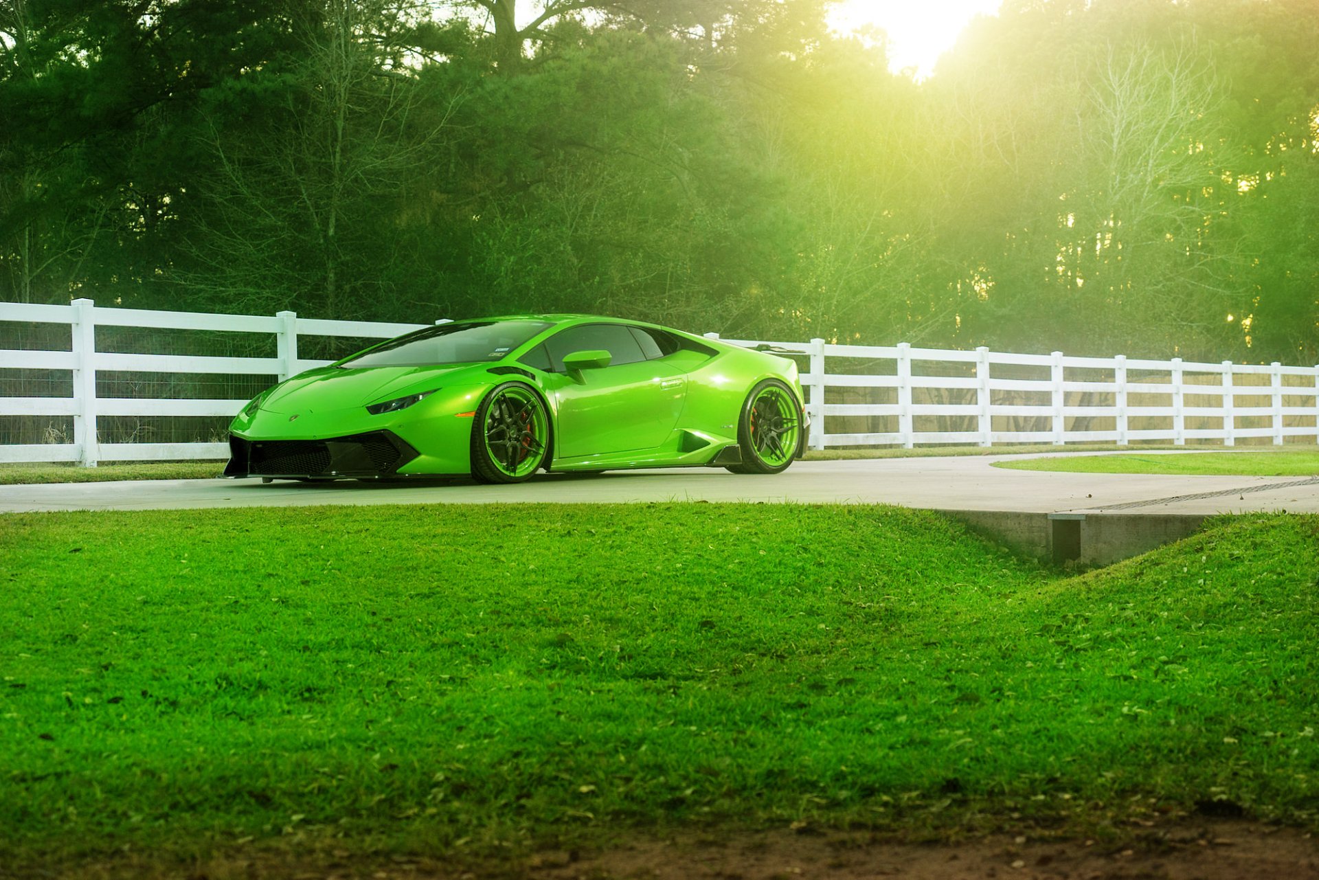 Green Lamborghini Huracan LP 610-4 supercar parked beside a white fence with sunlight filtering through trees, captured in HD for a PC desktop wallpaper.