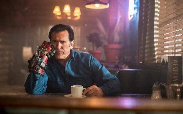 HD PC desktop wallpaper featuring Bruce Campbell as Ash from the TV show Ash vs. Evil Dead, sitting contemplatively with his signature mechanical hand in a dimly lit room.