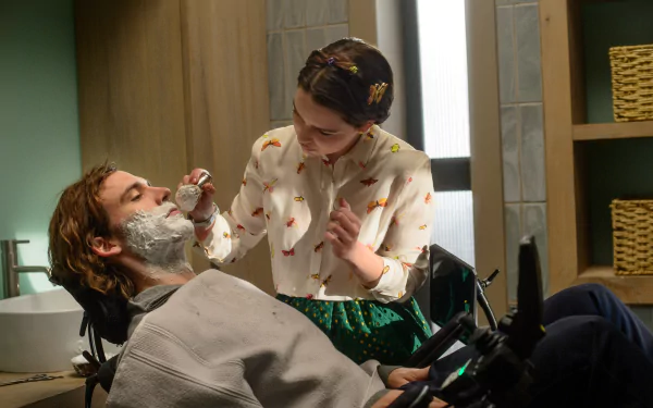 4K Ultra HD PC wallpaper: film scene of a woman tenderly shaving a reclining man in a wheelchair, warm lighting and vintage bathroom setting.