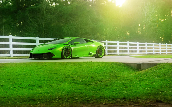 Green Lamborghini Huracan LP 610-4 supercar parked beside a white fence with sunlight filtering through trees, captured in HD for a PC desktop wallpaper.
