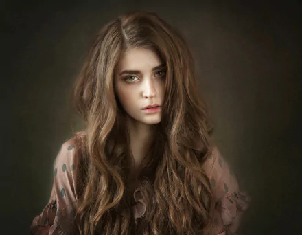 HD PC desktop wallpaper featuring a brunette woman model with long wavy hair and a soft, neutral expression against a dark, blurred background.