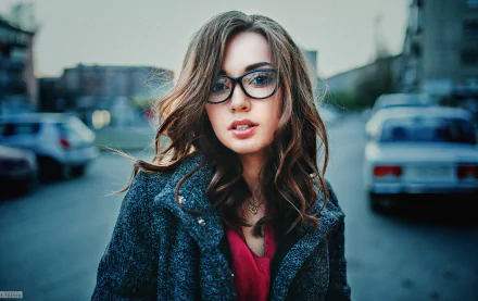 HD desktop wallpaper featuring a brunette woman wearing glasses, posing outdoors with a cityscape background.