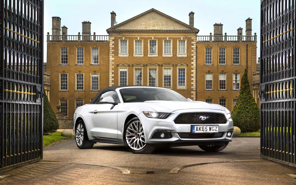 A sleek white Ford Mustang GT parked elegantly in front of a grand estate, framed by ornate gates, depicted in stunning 4K Ultra HD detail.