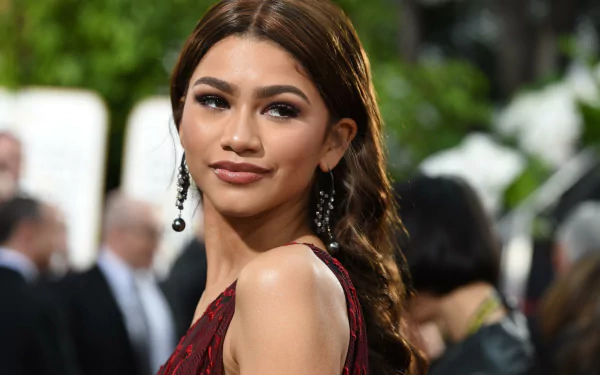 HD wallpaper featuring Zendaya, American singer and actress with brunette hair, brown eyes, and elegant earrings at a formal event.