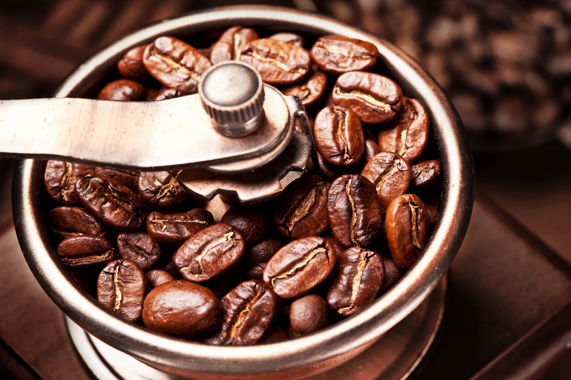 Close-up of roasted coffee beans inside a metal grinder, captured in sharp detail for a 4K Ultra HD PC desktop wallpaper and background.