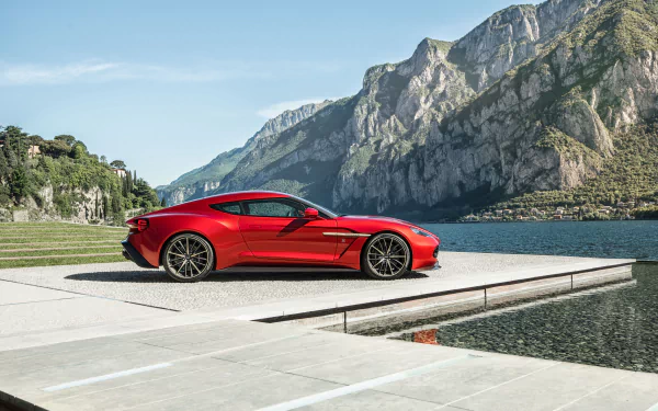 Red Aston Martin Vanquish grand tourer parked by a lake with mountainous backdrop, captured in stunning 4K Ultra HD as a PC desktop wallpaper and background.