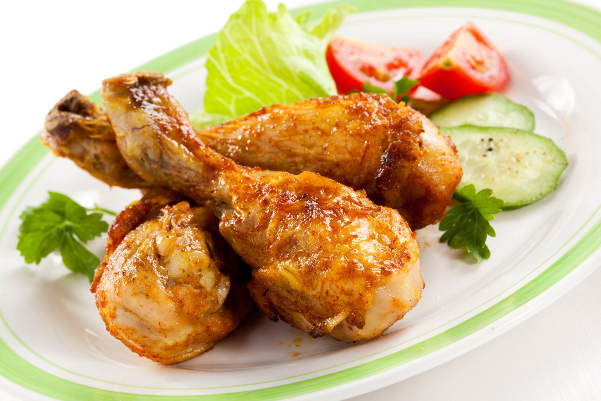 Golden-brown chicken drumsticks served on a plate with fresh lettuce, tomato slices, and cucumber, in a vibrant and appetizing arrangement as a 4K Ultra HD desktop wallpaper.