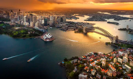A stunning aerial view of Sydney featuring the iconic Sydney Harbour Bridge and Sydney Opera House, surrounded by the vibrant Sydney skyline and tranquil harbor waters at sunset.