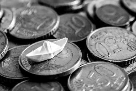HD PC desktop wallpaper and background showing a man-made origami paper boat resting on stacked coins, monochrome close-up.