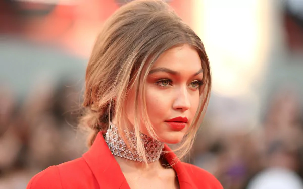 An HD desktop wallpaper featuring American model Gigi Hadid with blonde hair, wearing red lipstick and a sparkling necklace.