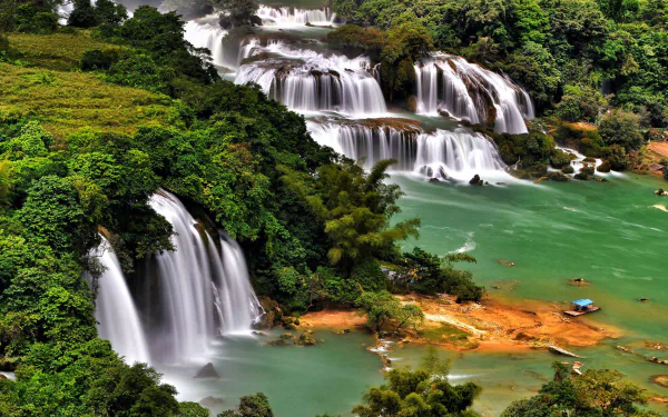 Ban Gioc-Detian Falls, a stunning waterfall on the China-Vietnam border, cascades through lush greenery into turquoise waters in this HD desktop wallpaper.