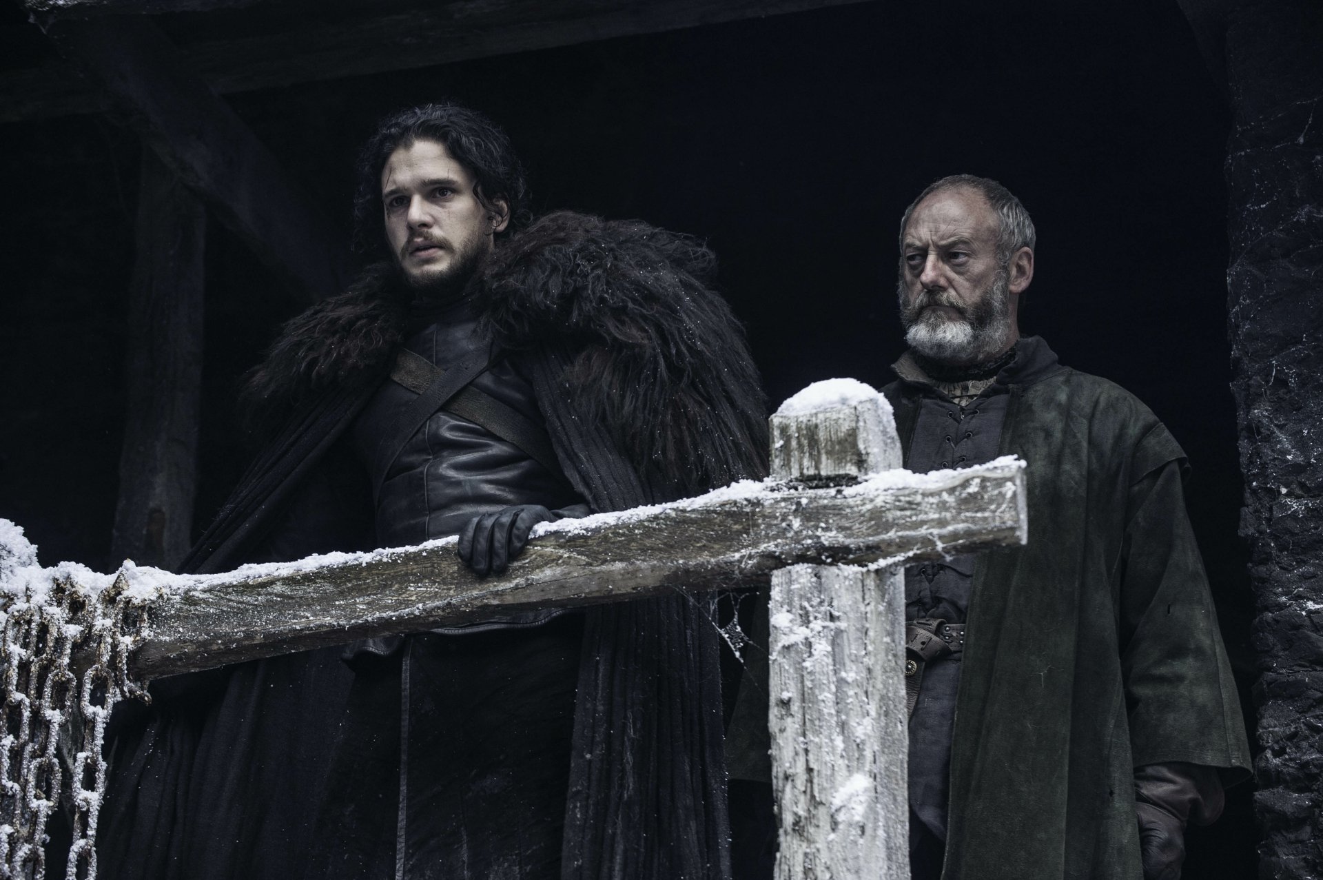 Jon Snow and Davos Seaworth on a snow-dusted wooden battlement, cloaked in black furs, brooding in a dark Game of Thrones 4K desktop wallpaper.