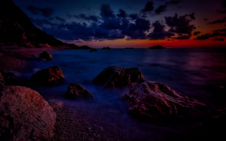 HD PC desktop wallpaper showcasing a dramatic HDR sunset over a rocky beach and calm ocean, highlighting the vibrant colors and natural beauty of the scene.