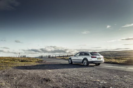 HD desktop wallpaper featuring a silver Audi A6 parked on a rural road under a cloudy sky, showcasing the sleek design of the vehicle in a natural landscape.