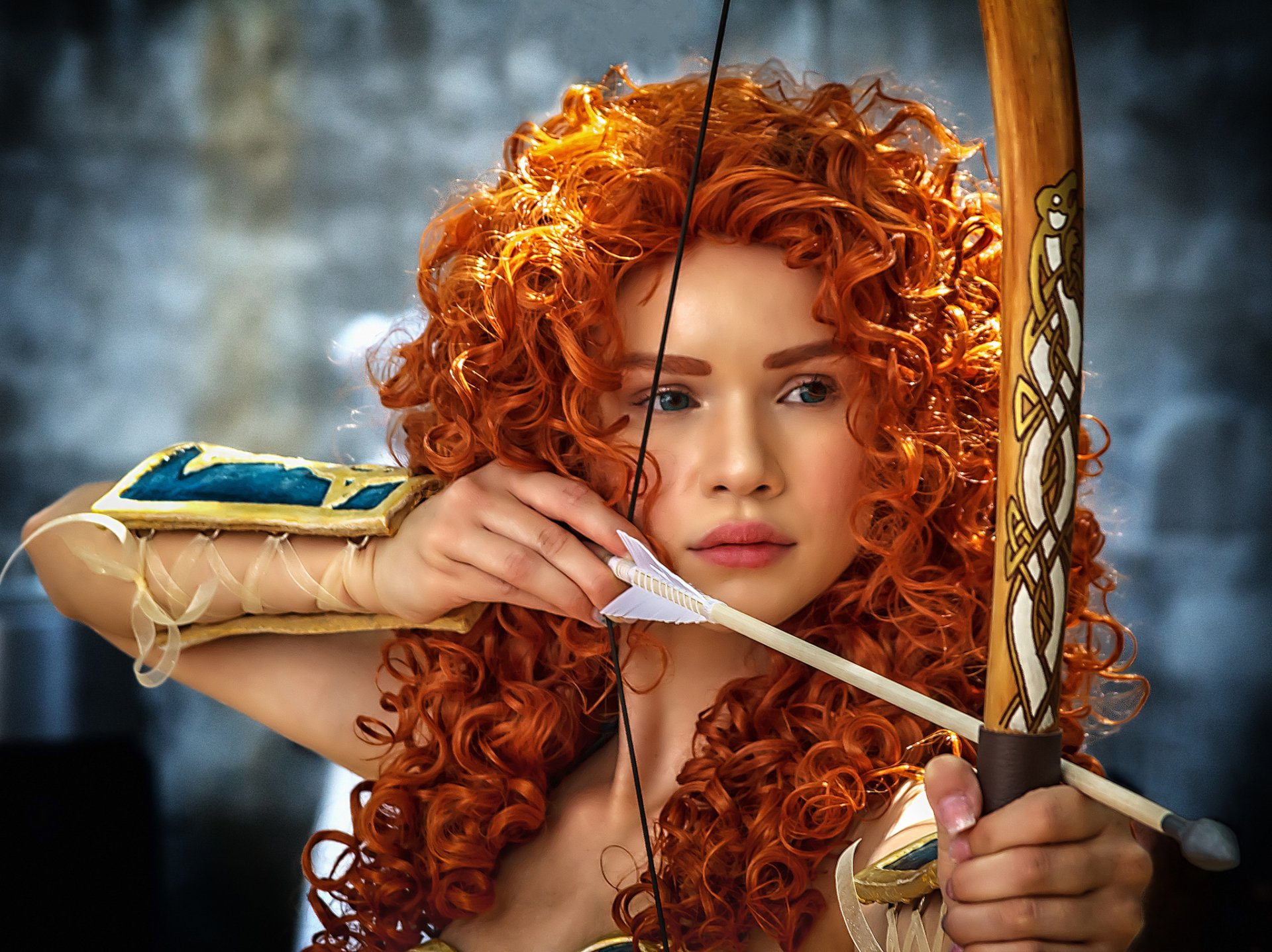 A woman with striking blue eyes and vibrant red hair focuses intently as she draws a bow, embodying a dynamic cosplay character in this HD desktop wallpaper.