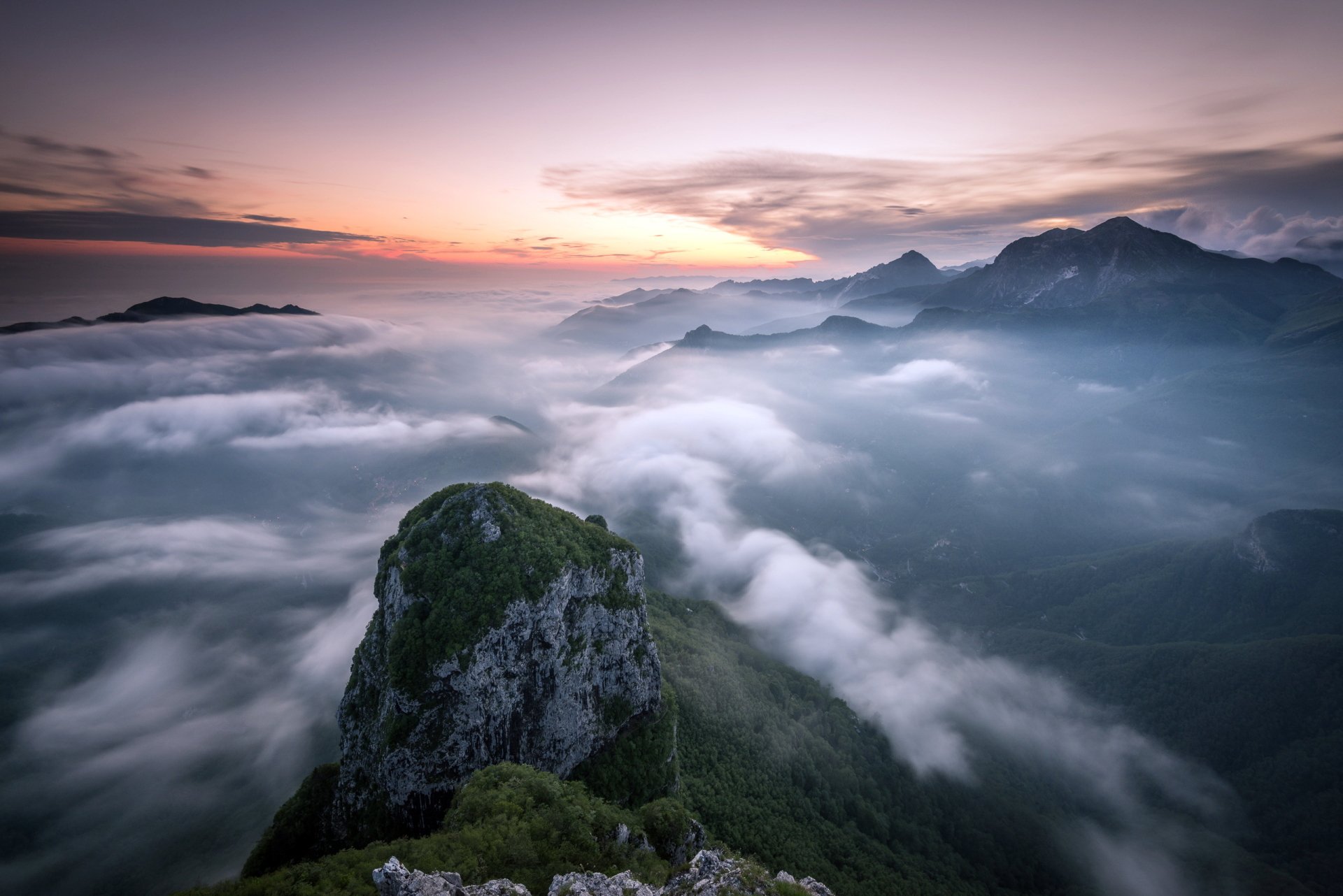 2K Quad HD PC desktop wallpaper: panoramic mountain landscape at the horizon, clouds and fog rolling through valleys under a pastel sky, serene nature view.