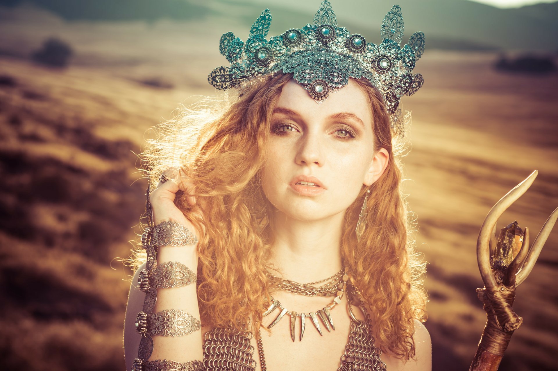 HD desktop wallpaper of redhead model Alexandria Basso wearing an ornate crown and necklace, with green eyes glowing in sunny, warm light.