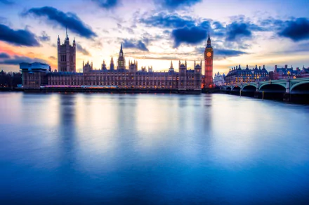 HD desktop wallpaper of the man-made Palace of Westminster and Big Ben beside the River Thames in London, United Kingdom, glowing at dusk with Westminster Bridge.