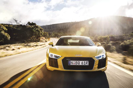 Front view of a yellow Audi R8 V10 supercar driving on a sunlit highway, captured in 4K Ultra HD as a vibrant PC desktop wallpaper.