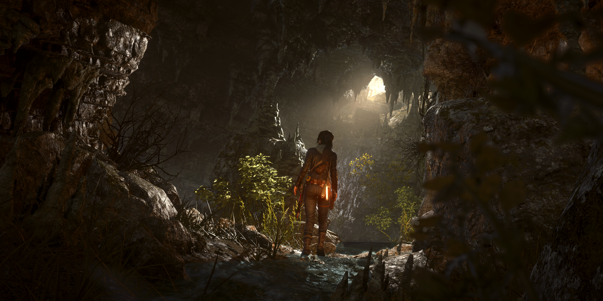 A scene from the video game Rise of the Tomb Raider, featuring a character exploring a dark cave illuminated by natural light, rendered in 8K Ultra HD for PC desktop.