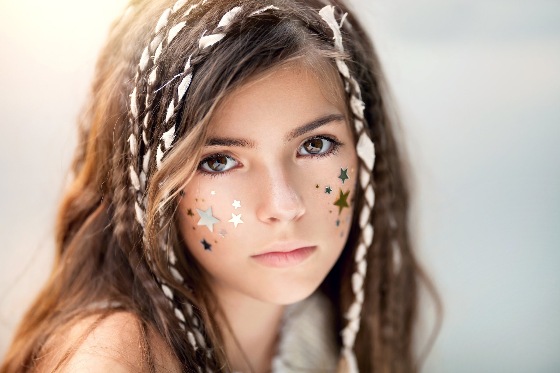 HD portrait of a brunette woman with brown eyes and braided hair, adorned with star-shaped face stickers, designed as a PC desktop wallpaper background.