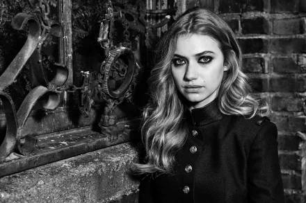 Black and white portrait of actress Imogen Poots, featuring dramatic makeup and a stylish black coat, set against a textured brick background. HD wallpaper for a striking display.