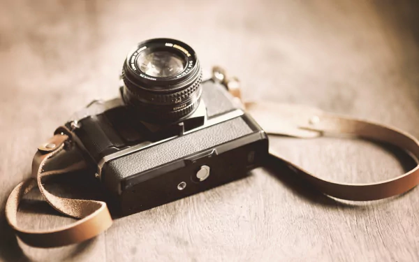 Man-made Minolta camera with leather strap on a wooden table, presented as an HD PC desktop wallpaper background.