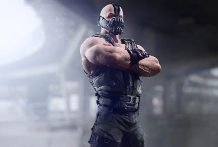 Bane from DC Comics stands confidently with crossed arms, portrayed in a high-definition wallpaper from The Dark Knight Rises, featuring a dramatic, atmospheric background.