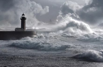 HD PC desktop wallpaper/background: towering waves crash against a man-made lighthouse on a stormy sea beneath brooding clouds.