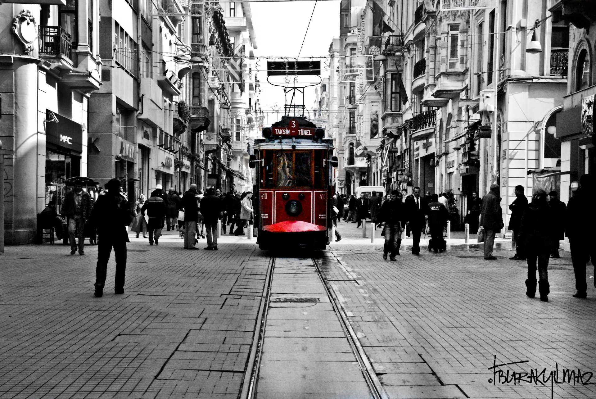 A vibrant red tram moves along a busy street in Turkey, surrounded by pedestrians and historic buildings in this 4K Ultra HD streetcar scene.