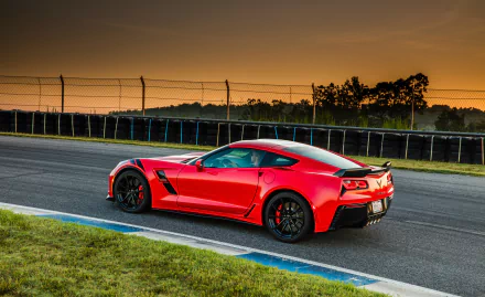 Red Chevrolet Corvette (C7) sports car on a racetrack at sunset — HD desktop wallpaper/background