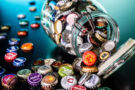 HD desktop wallpaper featuring a jar spilling colorful beer bottle caps onto a reflective surface, showcasing a vibrant and casual collection.