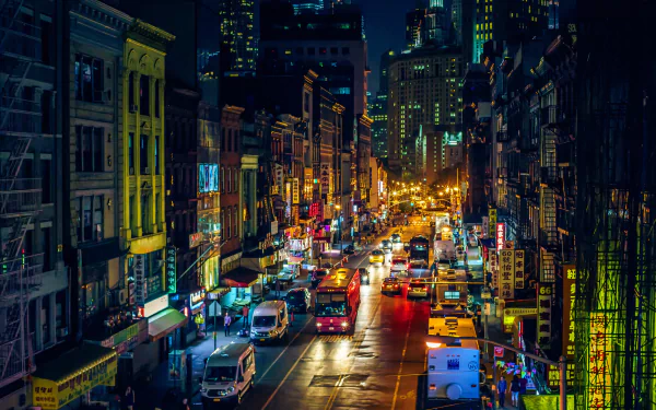 A vibrant night scene of Manhattan's Chinatown, featuring bustling streets illuminated by lights, with cars and buildings creating a dynamic urban backdrop in New York City.